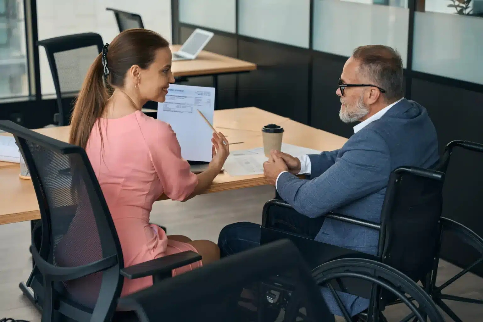 Woman showing man in wheelchair paperwork