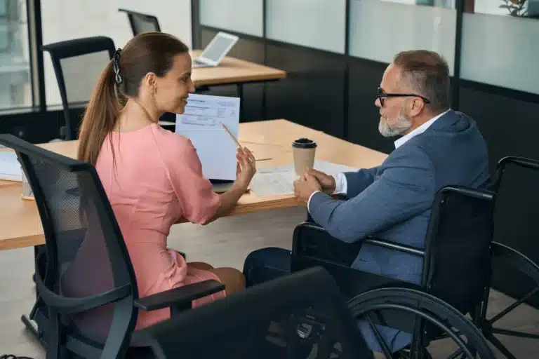 Woman showing man in wheelchair paperwork