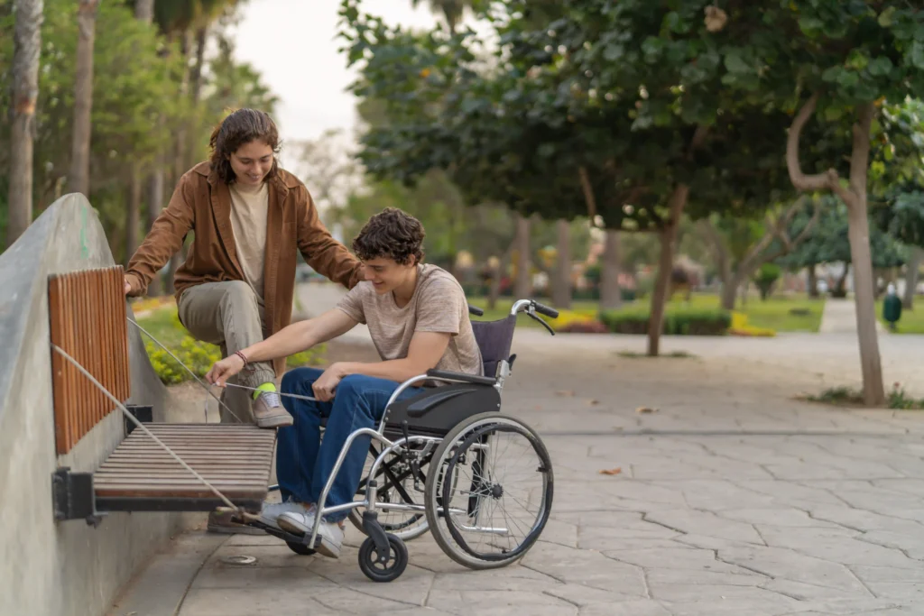 Young wheelchair bound man helping tie friends shoes