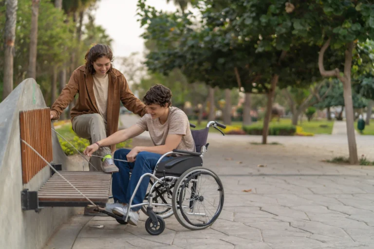 Young wheelchair bound man helping tie friends shoes