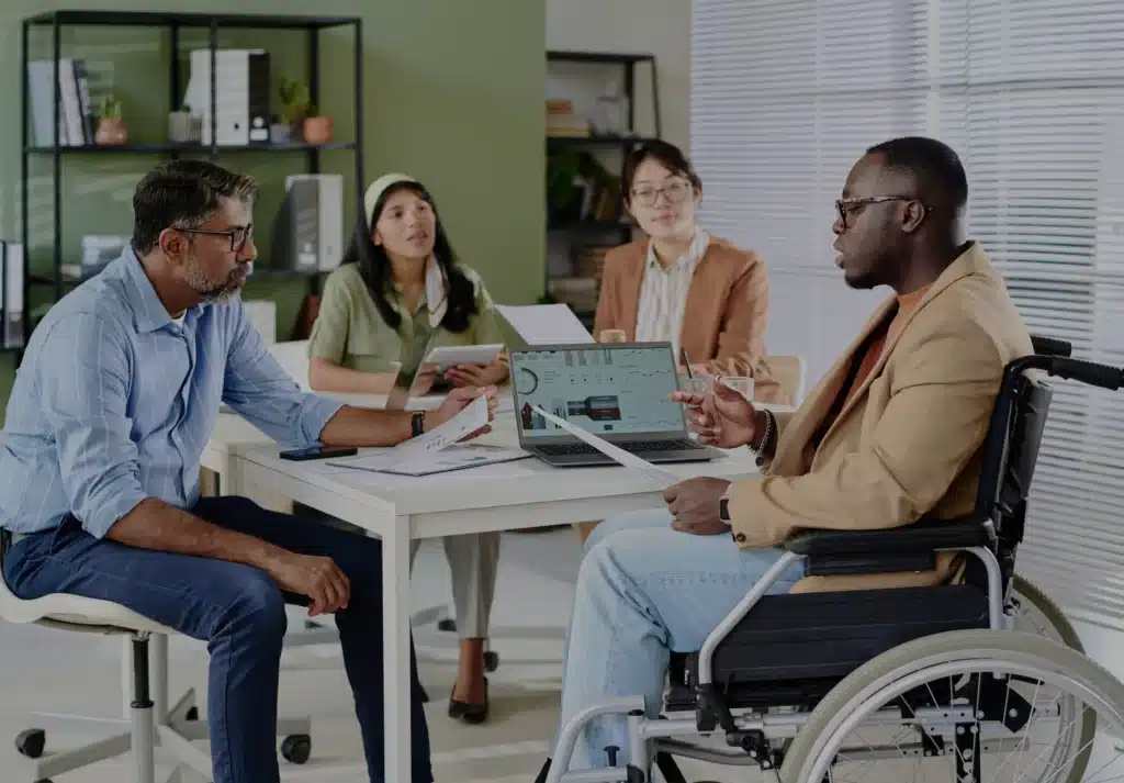 Workers around a table with one in a wheelchair