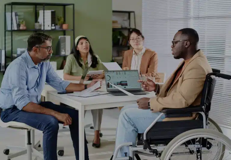 Workers around a table with one in a wheelchair