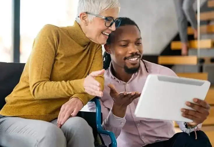 Young man showing woman in wheelchair papers